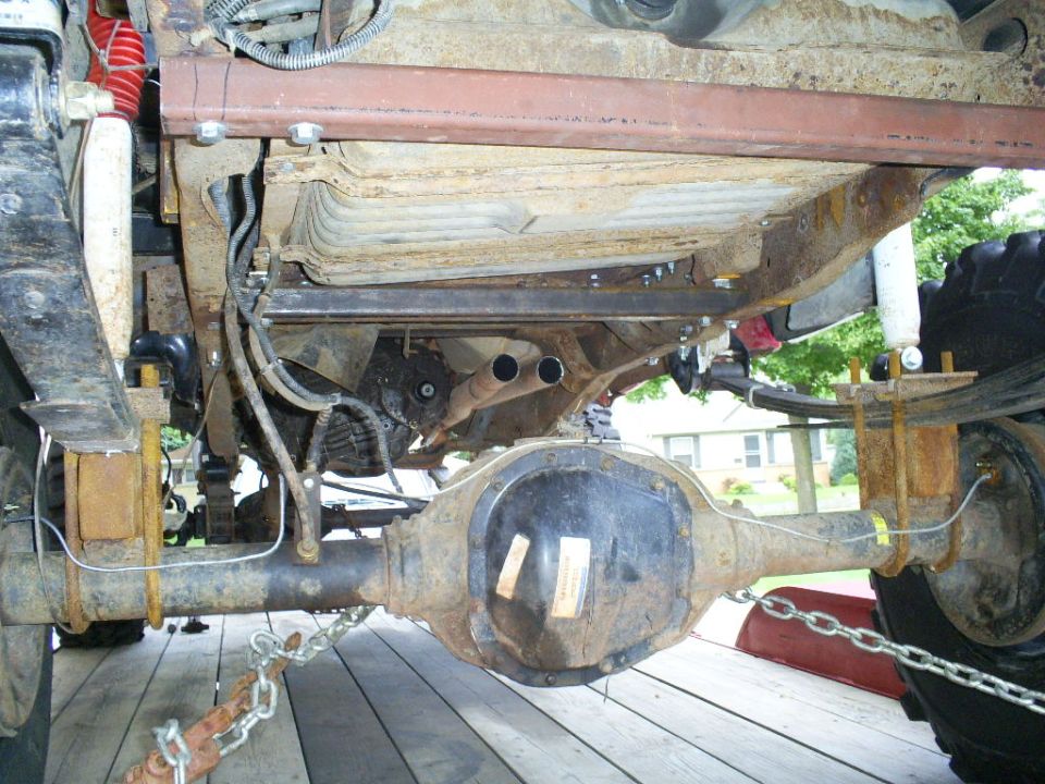 1994 Ford F-250 underside, showing rusty rear axle, leaf springs, fuel tank, and dual exhaust pipes