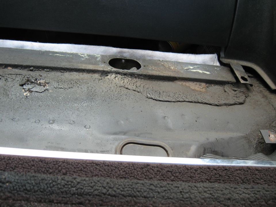Close-up of a car's interior floor pan with some rust and wear