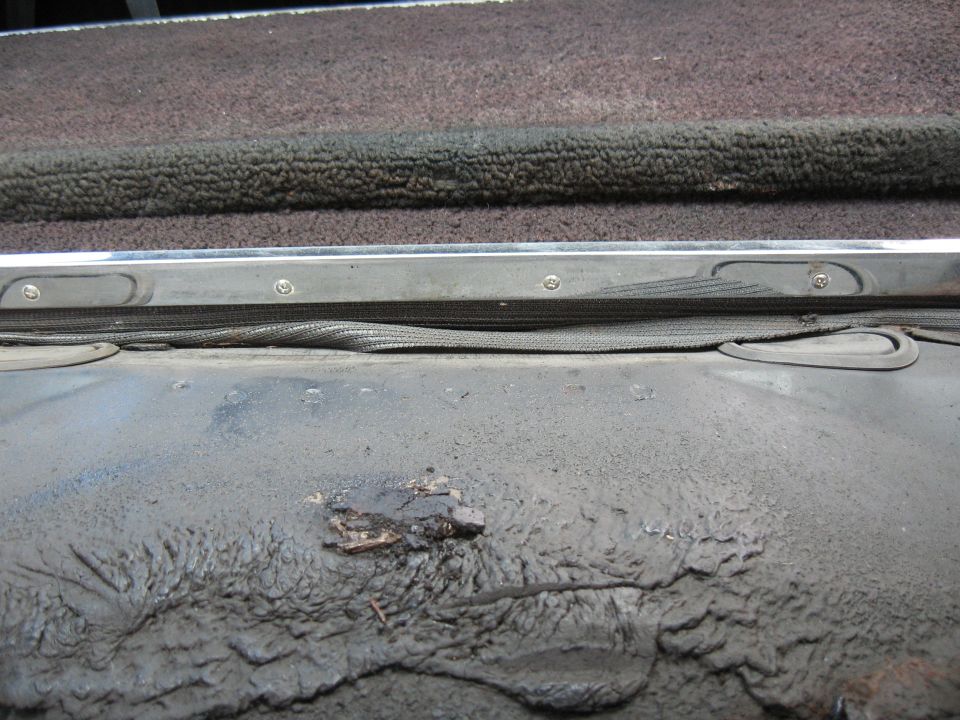 Car interior trim with textured fabric and metal strip, showing dirt and wear