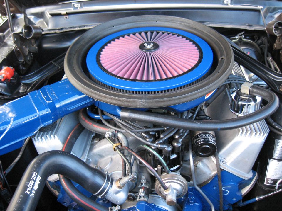 Engine bay showing a blue air intake with a pink filter, silver valve covers, and various hoses and wires