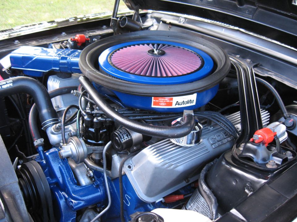 Close-up of a V8 engine with blue painted components, a large air cleaner, and 'COBRA' valve covers