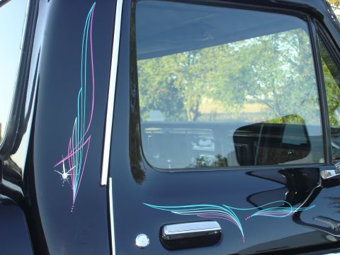 1979 Ford F-250 - A black truck door features custom pink and blue pinstriping along with a chrome door handle and side mirror.