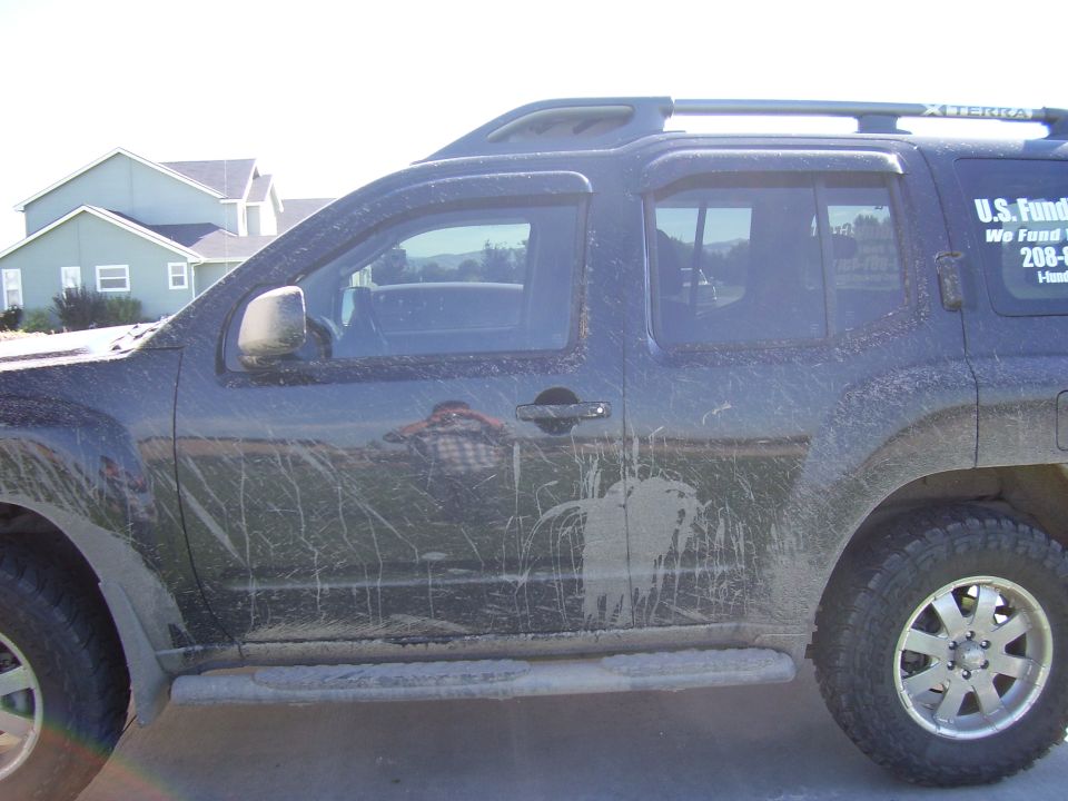 Mud-splattered black Nissan Xterra SUV parked in a driveway