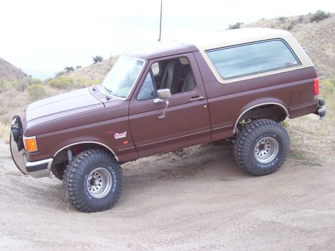 1990 Ford Bronco - This 1990 Ford Bronco, seen in a three-quarter front view, is equipped for off-road use on a dirt track.