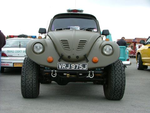 2001 Ford Fiesta - This modified Volkswagen Beetle features large off-road tires and a utilitarian paint scheme, parked alongside other vehicles.