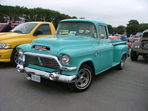 2001 Ford Fiesta - A classic teal GMC pickup truck is parked next to a yellow Dodge Ram pickup.