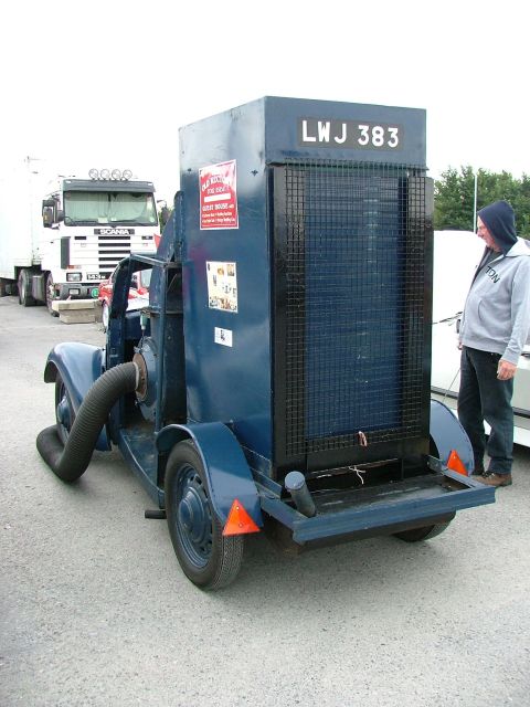 2001 Ford Fiesta - A man stands next to a blue industrial vacuum truck with a large hose attached to its side.