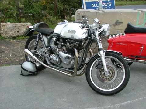 2001 Ford Fiesta - A custom chrome motorcycle is parked next to a red scooter, with a silver helmet resting on the pavement.