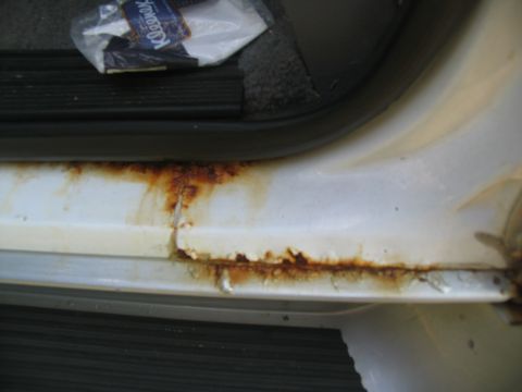 1995 Ford C-350 (Centurion Conversions) - The door sill of a vehicle exhibits extensive rust and corrosion, indicating potential structural issues.