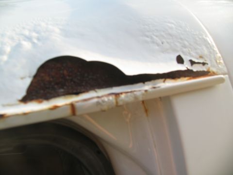 1995 Ford C-350 (Centurion Conversions) - Extensive rust damage is visible on the fender of a white vehicle.