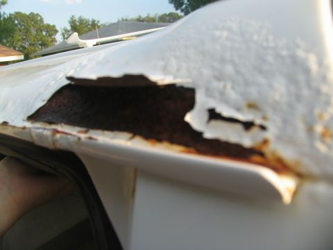 1995 Ford C-350 (Centurion Conversions) - The white paint is peeling away, revealing extensive rust underneath on the vehicle's roofline.