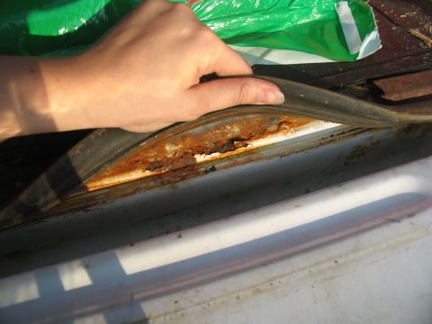 1995 Ford C-350 (Centurion Conversions) - Close-up view of a heavily rusted window seal, indicating potential body damage on a vehicle.