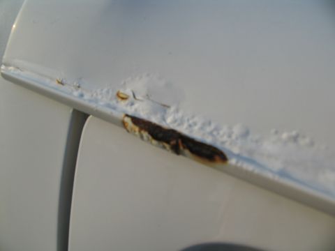 1995 Ford C-350 (Centurion Conversions) - Close-up of rust damage on a white vehicle door, indicating corrosion and paint failure.
