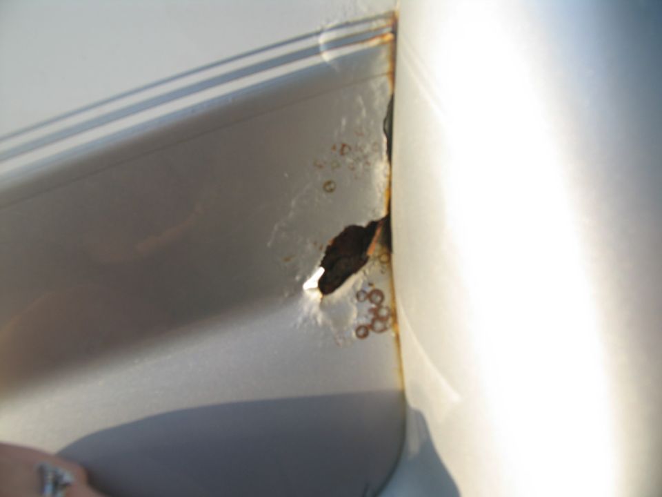 Rust hole on a silver vehicle panel
