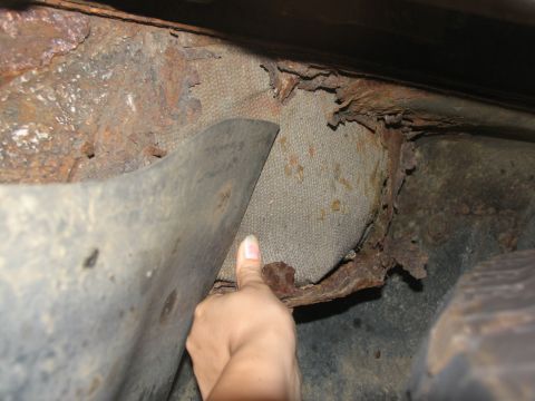 1995 Ford C-350 (Centurion Conversions) - Severe rust and deterioration visible on the undercarriage, with a hand pointing to fabric insulation.