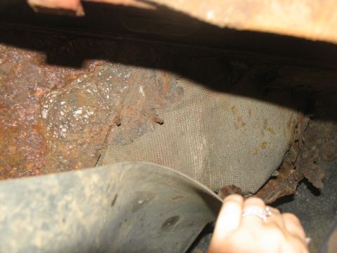 1995 Ford C-350 (Centurion Conversions) - The undercarriage of the vehicle shows significant rust and deterioration, with a fabric-like material visible beneath the corroded metal.