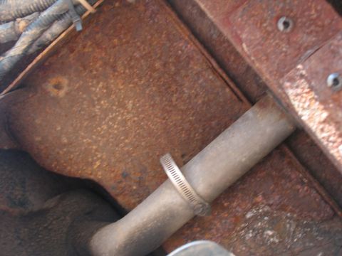 1995 Ford C-350 (Centurion Conversions) - Close-up of a rusted metal frame and exhaust pipe, showing signs of wear.