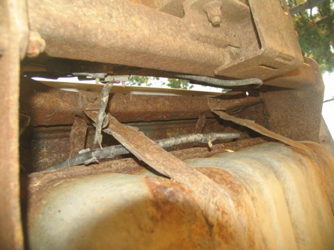 1995 Ford C-350 (Centurion Conversions) - The undercarriage of a vehicle shows a heavily rusted fuel tank with exposed wiring, indicating significant wear.
