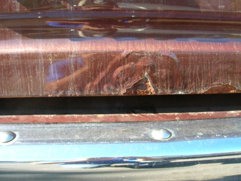 1979 Ford Bronco - Rust damage is visible on the lower body panel of a vehicle, just above the chrome bumper.