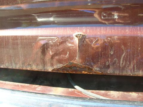 1979 Ford Bronco - This close-up shows significant rust and damage on a vehicle's body panel.