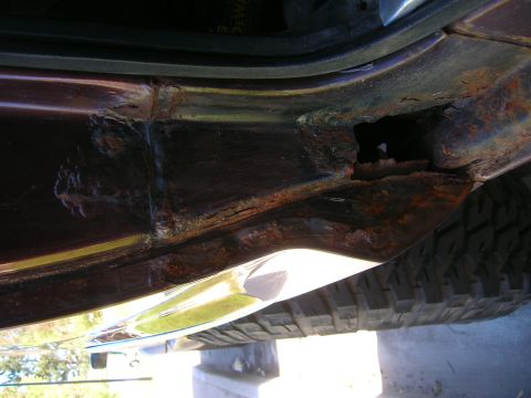 1979 Ford Bronco - Close-up of severe rust damage on a vehicle's rocker panel, with a tire visible underneath.