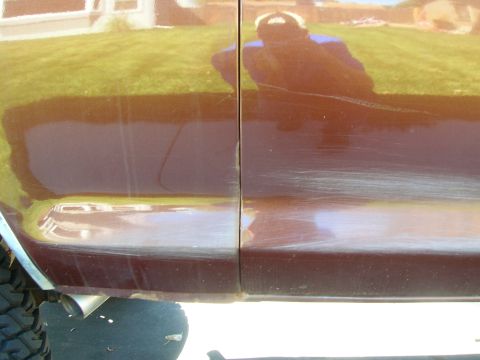 1979 Ford Bronco - Scratches and scuffs are visible along the door seam of this brown vehicle.