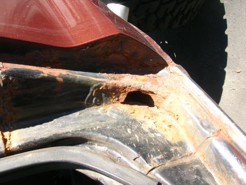 1979 Ford Bronco - Severe rust damage is visible in the fender well of this red vehicle.