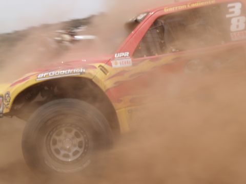 2000 Ford F-150 - A race truck speeds through the dirt, obscured by a cloud of dust.