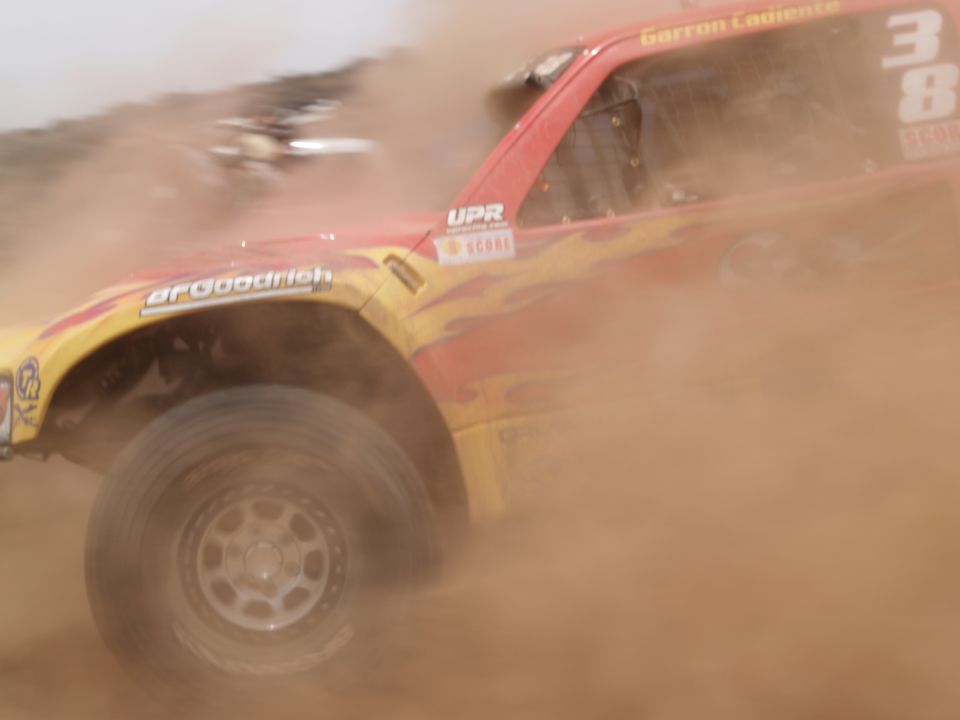 Off-road race truck kicking up dust, with 'BFGoodrich' and 'Garron Cadiente' visible