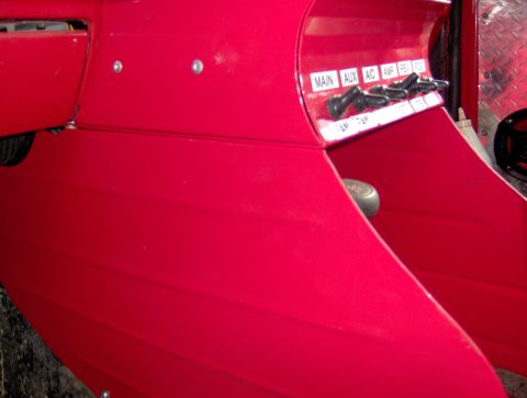 1978 Ford Bronco - Close-up of a red vehicle interior console with multiple labeled switches.