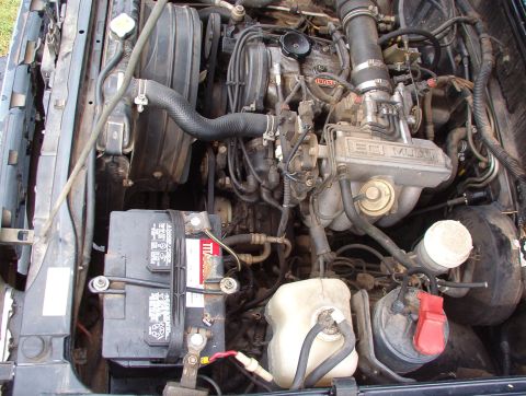 1993 Mitsubishi FTO - Close-up view of a vehicle's engine bay, showing the battery, radiator, and various engine parts.