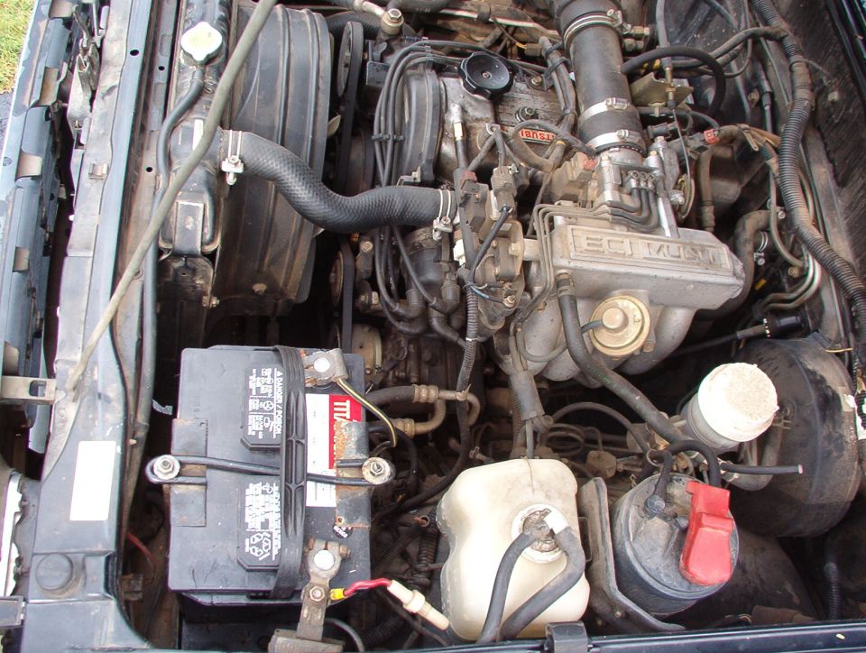 engine bay with battery, radiator, and engine components visible