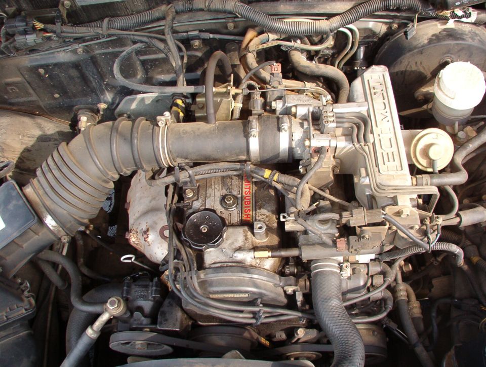 Engine bay of a 1993 Mitsubishi FTO, showing the engine with visible "MITSUBISHI" text on a part