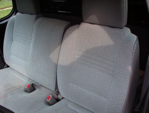 1993 Mitsubishi FTO - The interior rear seats of a vehicle are shown, patterned upholstery and visible seatbelts.