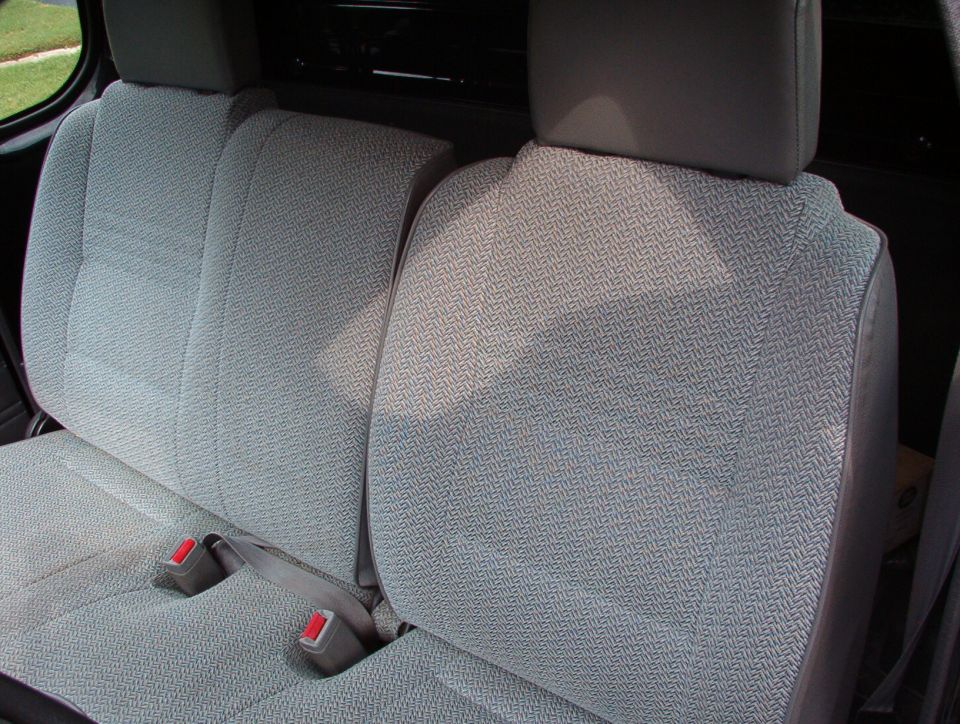Back seat with patterned cloth upholstery and seatbelts