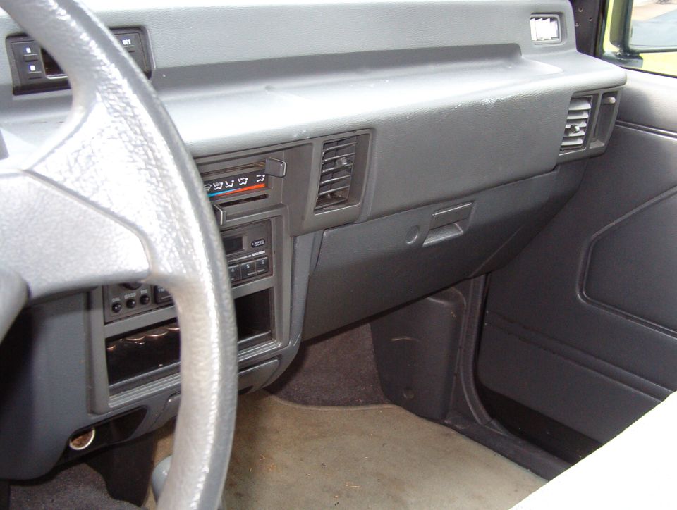 Gray 1980s-90s dashboard with slider HVAC controls, vents and steering wheel