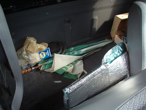 1993 Mitsubishi FTO - The interior of a vehicle's back seat area contains various items including a NAPA belt and an umbrella.