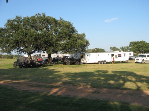 2001 Jeep Wrangler - Multiple Jeeps and trailers are parked in a grassy area with large trees providing shade.