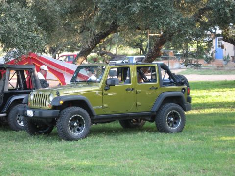 2001 Jeep Wrangler - A green Jeep Wrangler, identified as a Rubicon model, is parked on a grassy area next to another vehicle.