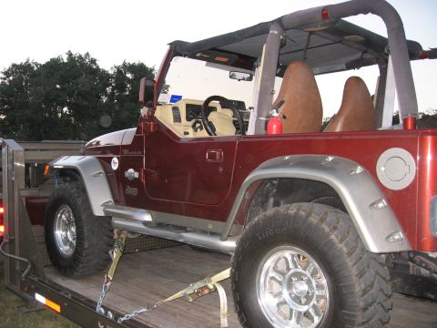 2001 Jeep Wrangler - This 2001 Jeep Wrangler is secured to a trailer, ready for transport. The vehicle features a red exterior and tan interior.