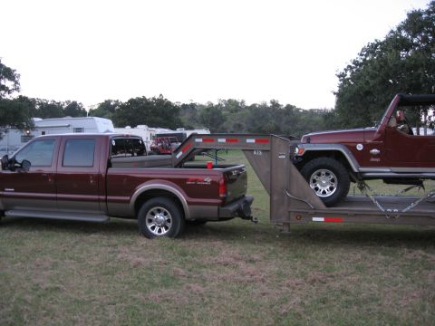 2001 Jeep Wrangler - A maroon pickup truck tows a trailer carrying a red 2001 Jeep Wrangler.