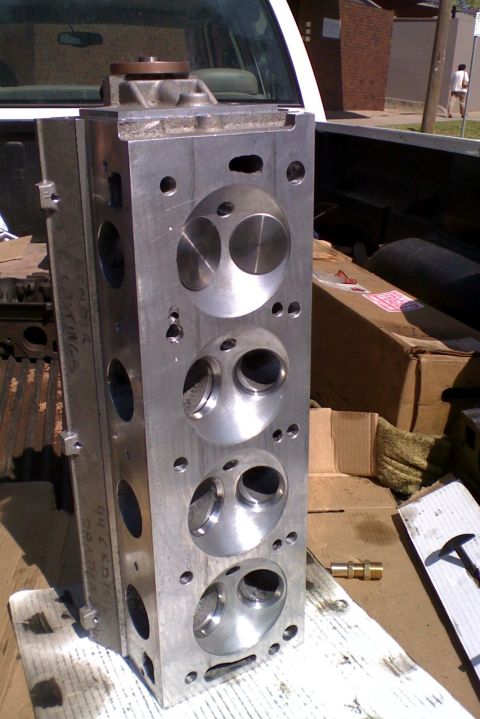 1964 Ford 427 - Aluminum V8 engine cylinder head with four intake and four exhaust ports, resting in a truck bed.