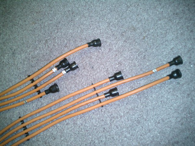 Orange spark plug wires with black connectors on a carpeted surface