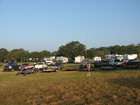 2001 Jeep Wrangler - A collection of vehicles and recreational vehicles are parked in an open, grassy area under a clear sky.