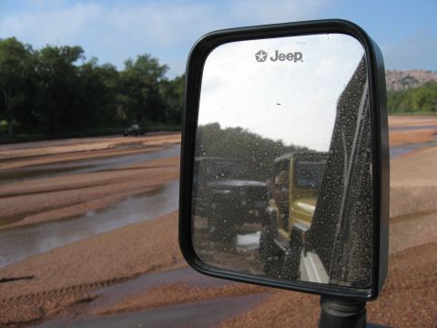 2001 Jeep Wrangler - Reflection in the side mirror shows two Jeeps on a dirt road with trees and a river in the background.