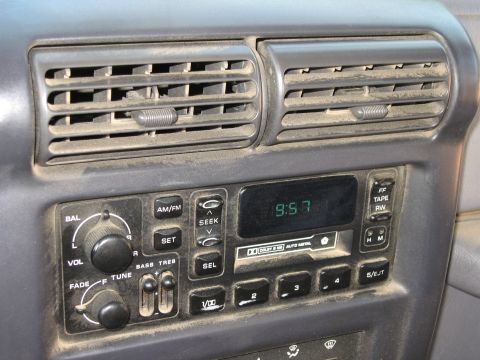 2001 Jeep Wrangler - Interior view of a car's dashboard, air vents and a radio unit with a digital display.