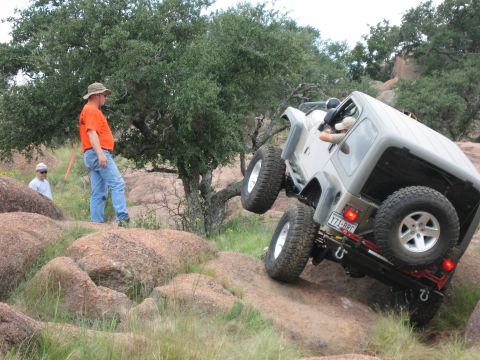 2001 Jeep Wrangler - A 2001 Jeep Wrangler navigates a challenging rocky obstacle with one wheel lifted.