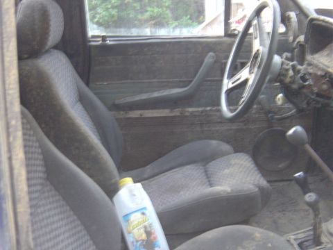 1987 Suzuki Samurai - The interior of this vehicle is very dirty, with a bottle of windshield washer fluid visible.