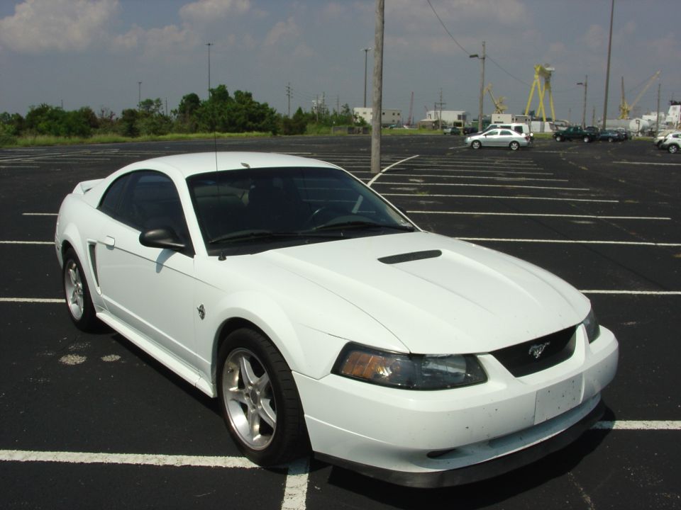 White 1999 Ford Mustang coupe parked in an empty lot