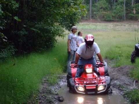1992 Ford F-150 - An ATV navigates through a muddy trail with onlookers present.